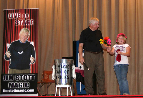 Jim Stott performing a magic trick with the help of an enthusiastic audience volunteer